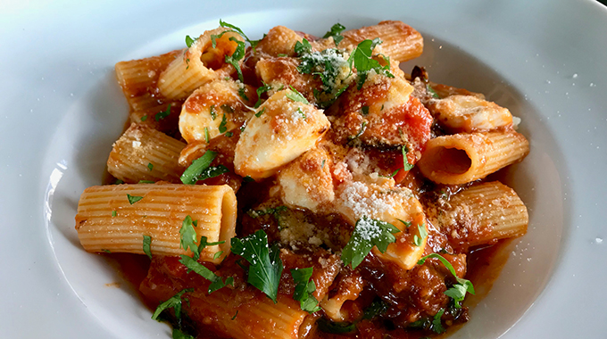 Rigatoni Pasta with Eggplant, Tomato Sauce, Mozarella, Parmesan Cheese and  Basil Leaves served at Restaurant.
